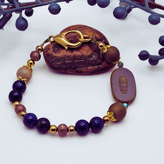 Elegant clasp bracelet with shades of blue and purple and a Czech glass purple oval focal. Gold lobster clasp.