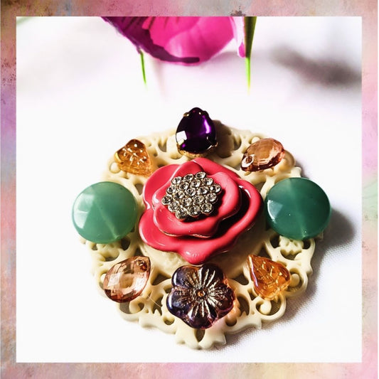 Add a playful touch of vintage flair to your outfit with a Pink Flower on Cream Background Brooch! This unconventional accessory features a hot pink vintage flower surrounded by Czech glass and colorful elements, all set on a cream filigree base. A must-have for any fashion lover looking for a unique piece and a unique gift.